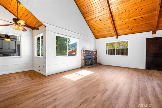 unfurnished living room featuring beamed ceiling, hardwood / wood-style floors, wood ceiling, a wood stove, and high vaulted ceiling