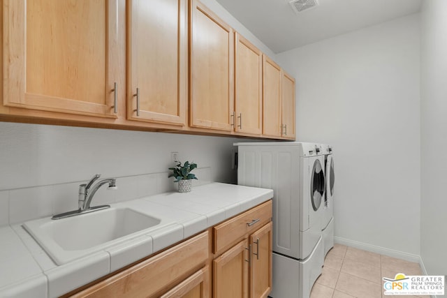 washroom with light tile patterned floors, cabinets, sink, and washing machine and clothes dryer