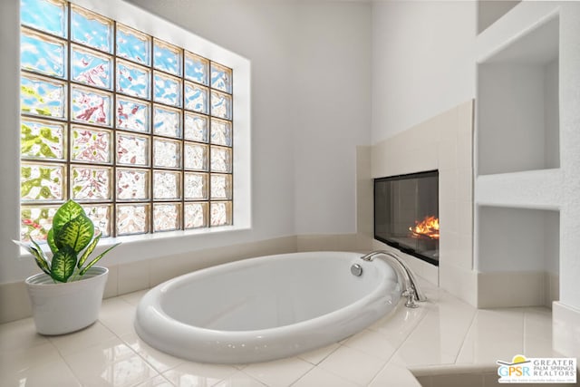 bathroom featuring a tiled fireplace and a relaxing tiled tub