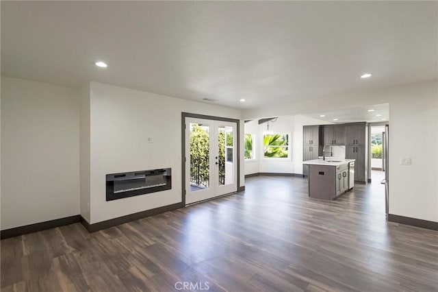 unfurnished living room with heating unit, sink, dark wood-type flooring, and french doors