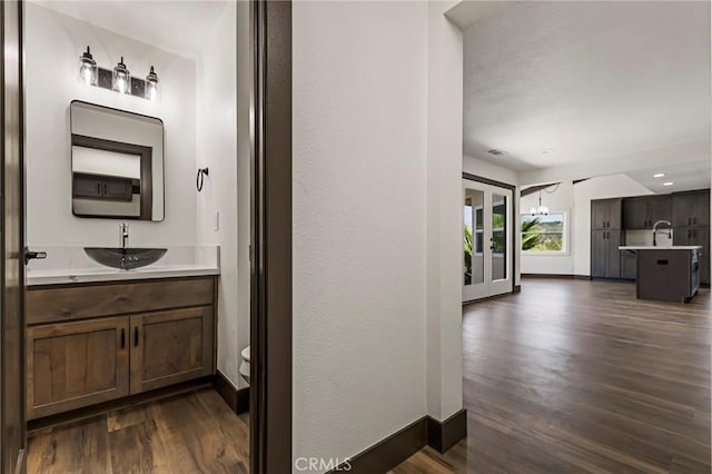 bathroom with hardwood / wood-style flooring, vanity, toilet, and a chandelier