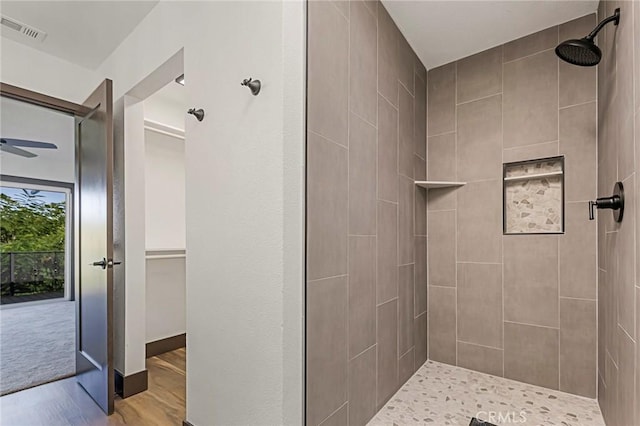 bathroom with hardwood / wood-style floors and a tile shower