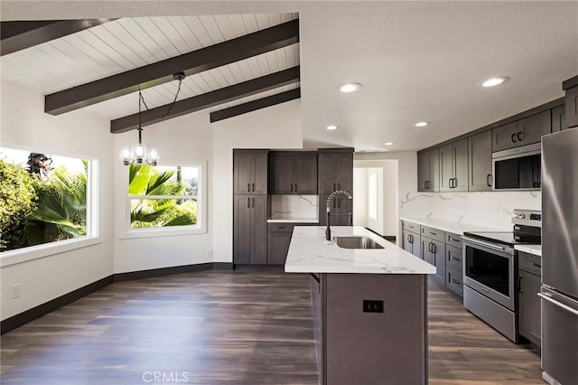 kitchen featuring appliances with stainless steel finishes, lofted ceiling with beams, sink, a kitchen island with sink, and light stone countertops