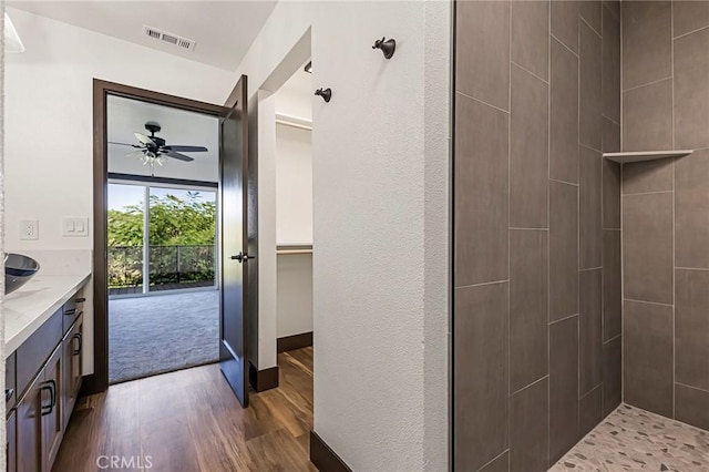 bathroom with vanity, hardwood / wood-style floors, ceiling fan, and a tile shower