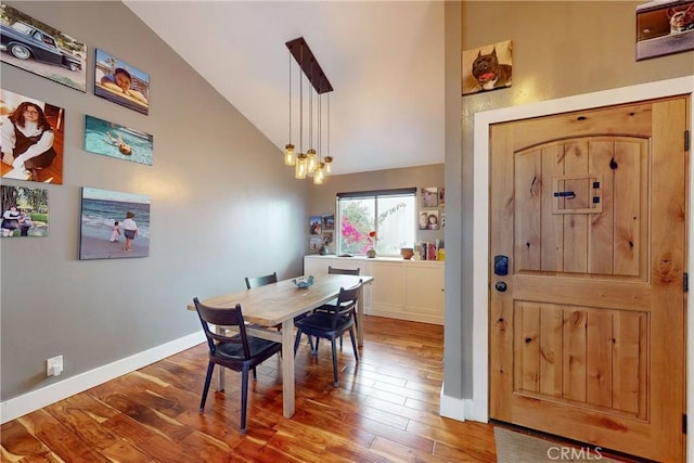 dining space featuring hardwood / wood-style flooring and high vaulted ceiling