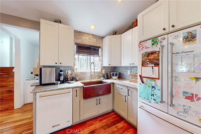 kitchen with white cabinetry, high quality fridge, dishwasher, and sink