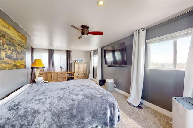 bedroom with ceiling fan, light colored carpet, and multiple windows