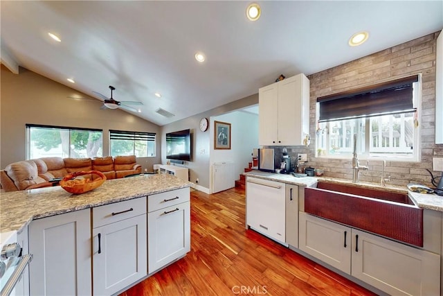 kitchen with lofted ceiling, sink, dishwasher, white cabinetry, and light hardwood / wood-style floors