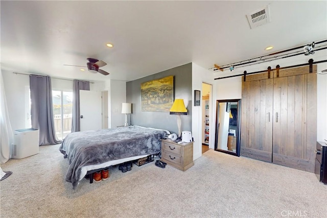 bedroom featuring access to exterior, light colored carpet, a barn door, and ceiling fan