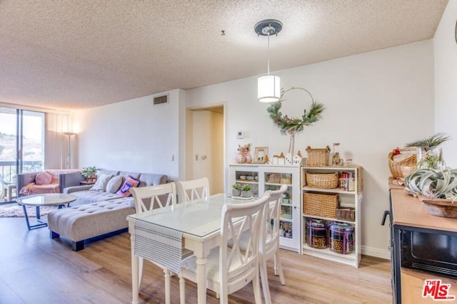 dining area with a textured ceiling and light hardwood / wood-style flooring