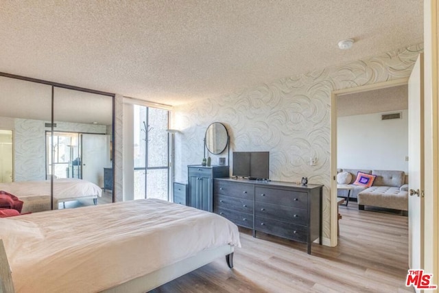 bedroom with light wood-type flooring and a textured ceiling