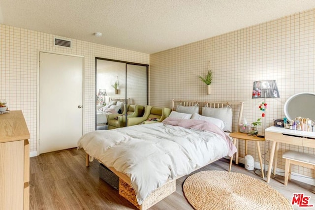 bedroom with a textured ceiling, a closet, and hardwood / wood-style floors