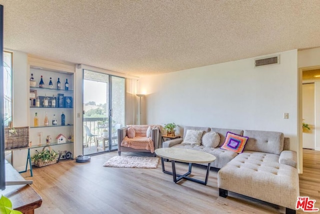 living room with wood-type flooring, a textured ceiling, and a wall of windows