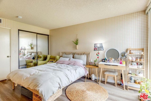 bedroom with a textured ceiling, a closet, and hardwood / wood-style floors