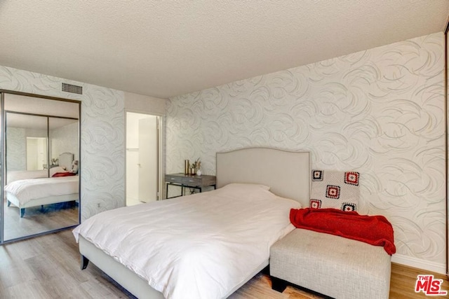 bedroom featuring a textured ceiling, a closet, and hardwood / wood-style flooring