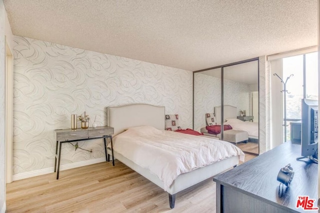 bedroom with a textured ceiling, wood-type flooring, and a closet