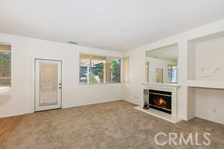 unfurnished living room featuring a healthy amount of sunlight and carpet flooring