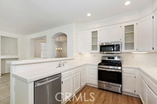 kitchen featuring stainless steel appliances, kitchen peninsula, and white cabinetry