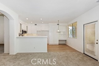 kitchen featuring pendant lighting, light colored carpet, and white cabinets