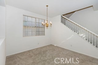 spare room featuring a notable chandelier and carpet flooring