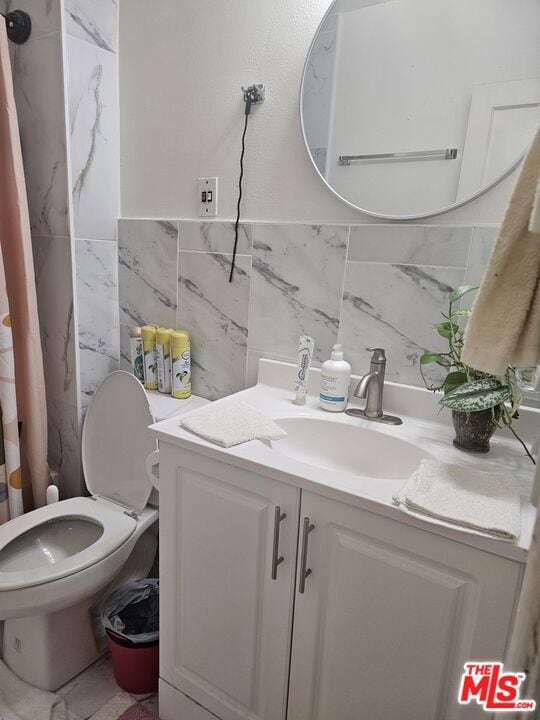 bathroom with a shower with curtain, vanity, tile walls, and toilet