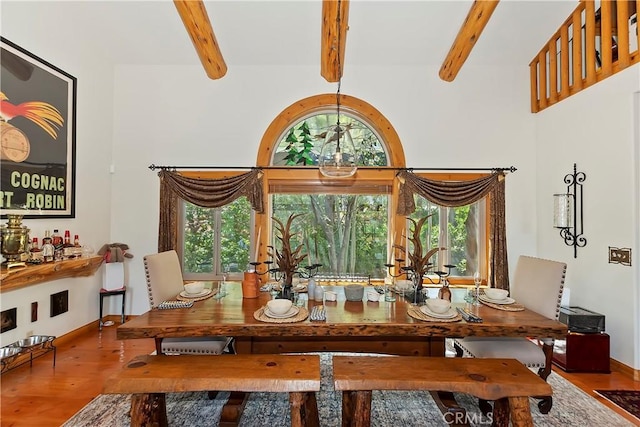 dining space with a wealth of natural light, wood-type flooring, and beamed ceiling