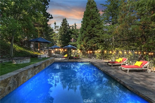 pool at dusk featuring a patio area