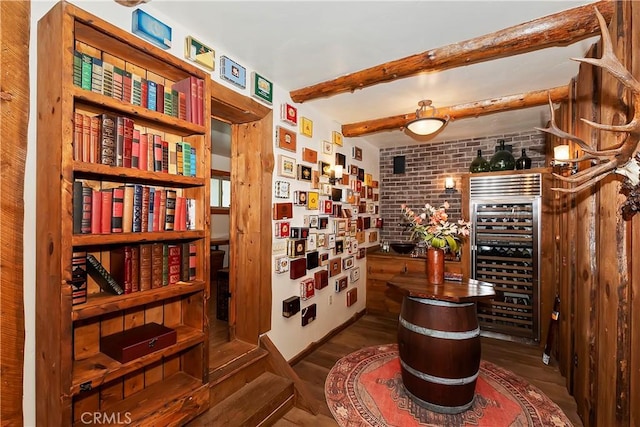 wine room with brick wall, hardwood / wood-style floors, beamed ceiling, and wine cooler