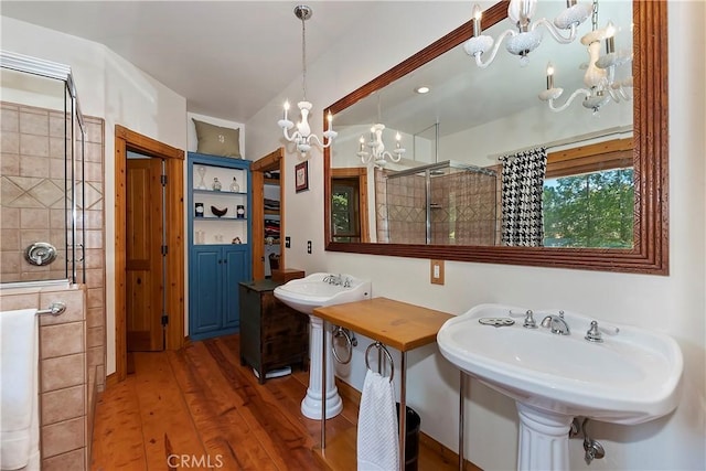 bathroom with a chandelier, wood-type flooring, and tiled shower