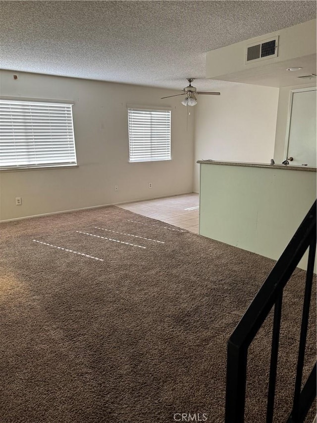 spare room with ceiling fan, light colored carpet, and a textured ceiling