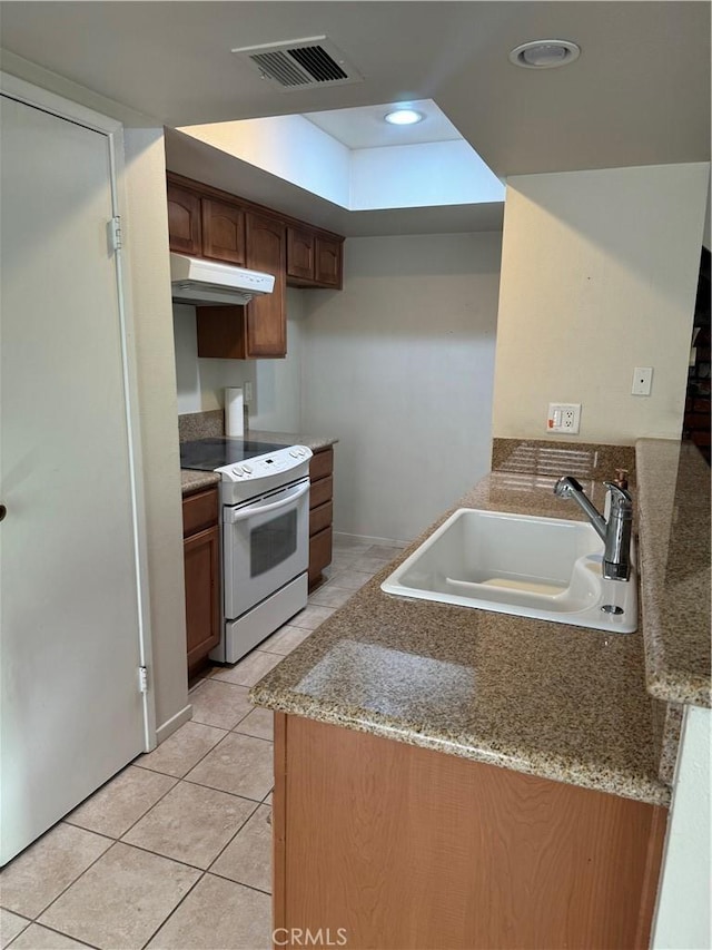 kitchen with light stone counters, white electric range, sink, and light tile patterned floors