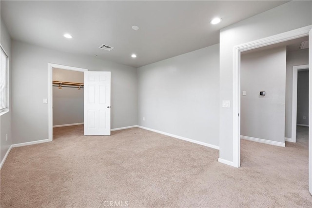 unfurnished bedroom with a walk in closet, light carpet, and a closet