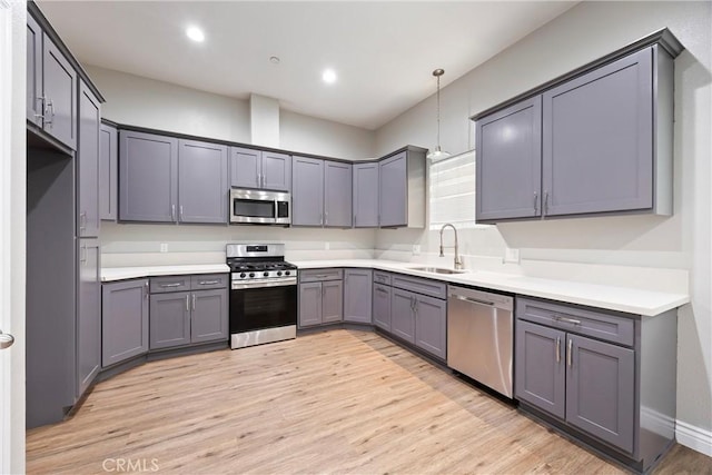 kitchen featuring light hardwood / wood-style floors, sink, hanging light fixtures, and appliances with stainless steel finishes