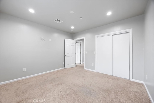 unfurnished bedroom with light carpet and a closet