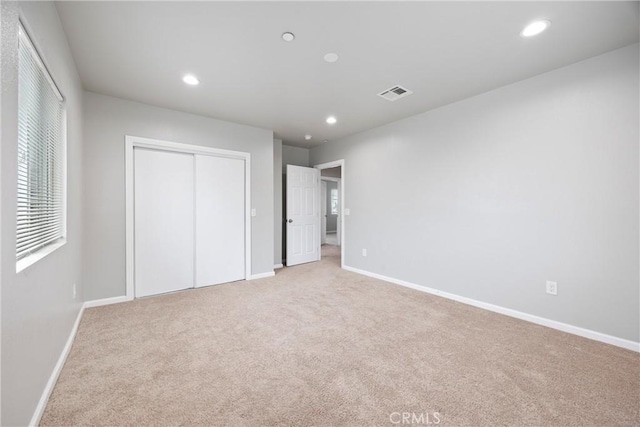 unfurnished bedroom featuring light colored carpet and a closet