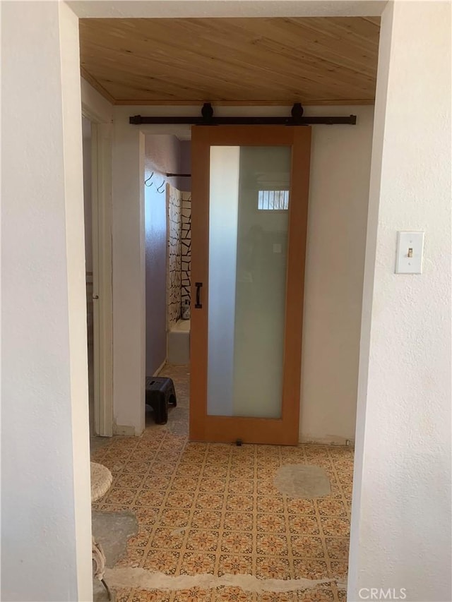 hallway featuring a barn door and wooden ceiling