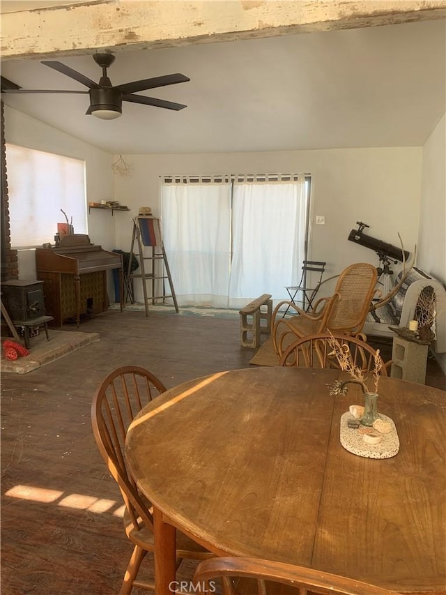 dining room with a wood stove, ceiling fan, and dark wood-type flooring