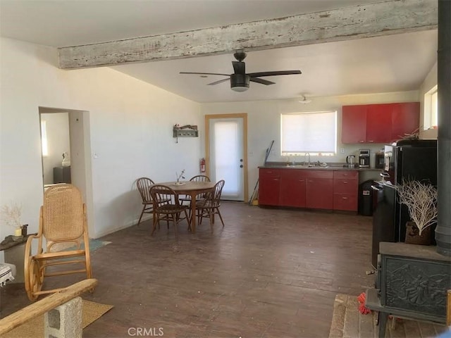 dining space with ceiling fan, sink, beamed ceiling, and dark wood-type flooring