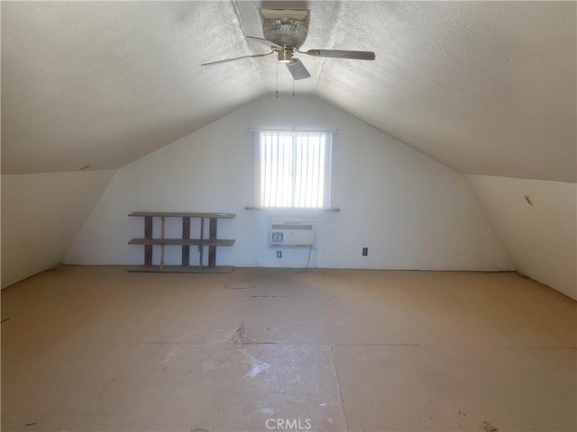 additional living space featuring a textured ceiling, vaulted ceiling, a wall mounted AC, and ceiling fan