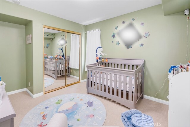 carpeted bedroom featuring a nursery area, a closet, and baseboards