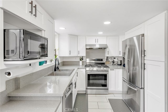 kitchen with light tile patterned floors, stainless steel appliances, white cabinets, a sink, and under cabinet range hood