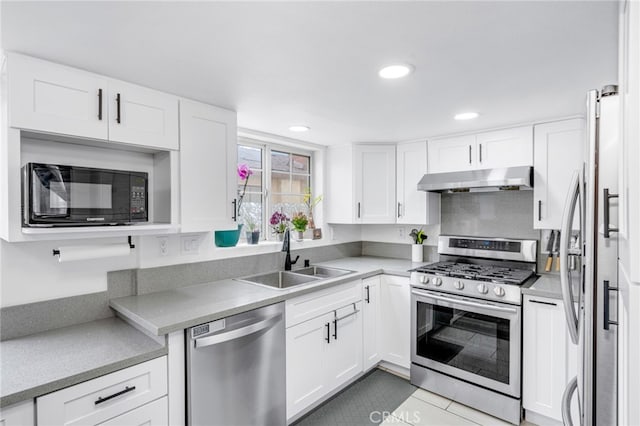 kitchen with under cabinet range hood, white cabinetry, stainless steel appliances, and a sink