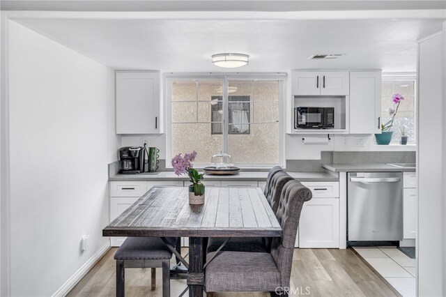 kitchen with visible vents, stainless steel dishwasher, white cabinetry, light wood-type flooring, and black microwave