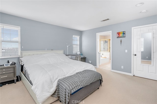 bedroom featuring baseboards, visible vents, connected bathroom, and light colored carpet