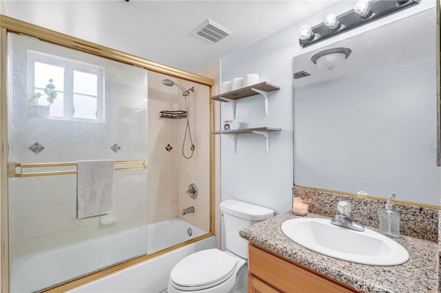 full bath featuring toilet, visible vents, bath / shower combo with glass door, and vanity