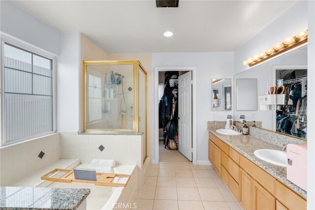 bathroom featuring a shower stall, a spacious closet, a sink, and tile patterned floors