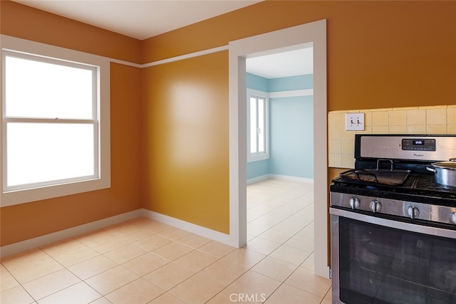 kitchen with light tile patterned floors, gas stove, and tasteful backsplash