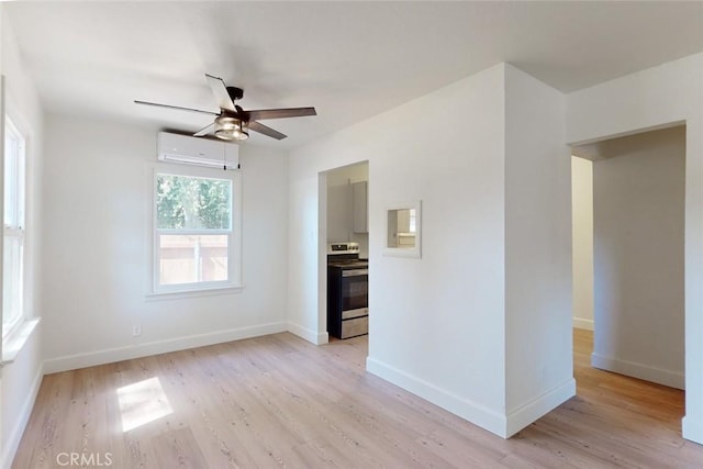 spare room featuring ceiling fan, light hardwood / wood-style floors, and an AC wall unit