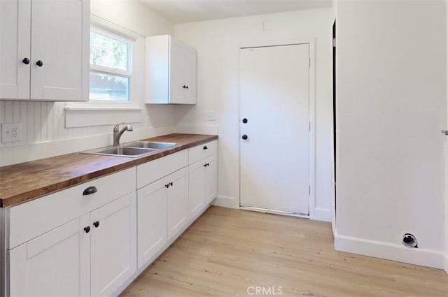 kitchen with sink, white cabinetry, wooden counters, and light wood-type flooring