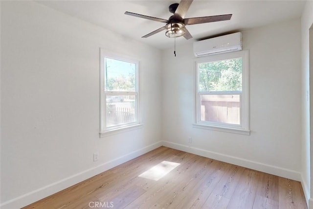 empty room featuring an AC wall unit, ceiling fan, and light wood-type flooring